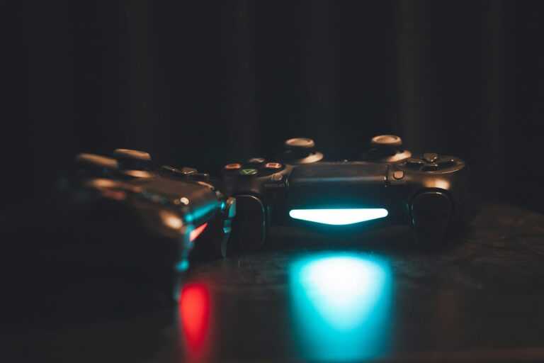 Close-up of glowing gaming controllers on a dark surface, creating a moody ambiance.